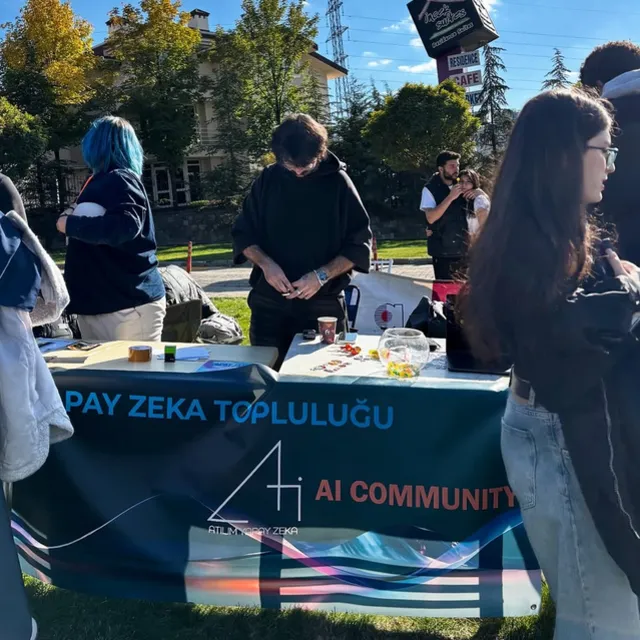 Atılım AI standı: masaya asılı “Yapay Zeka Topluluğu – AI Community” pankartı ve çevresindeki öğrenciler.